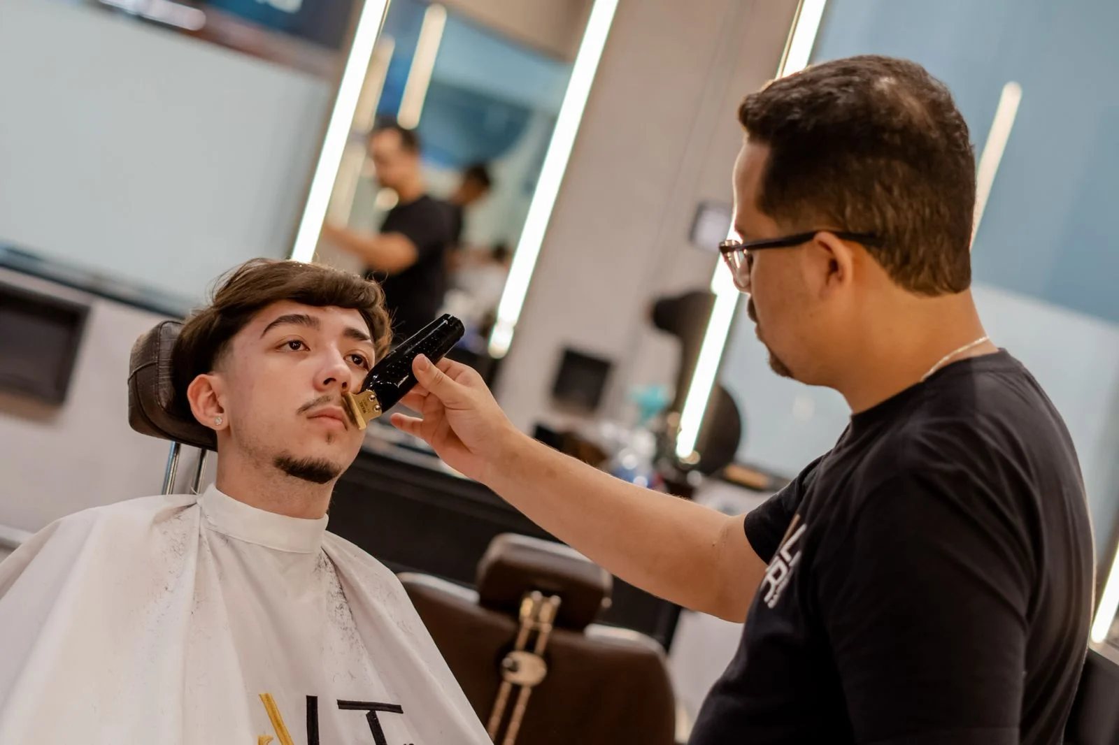 Barbeiro finalizando o corte de um cliente com secador