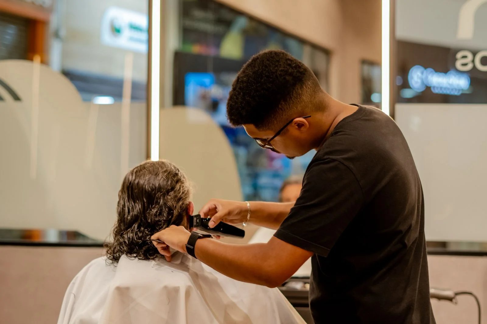Barbeiro cortando o cabelo de um cliente diante do espelho