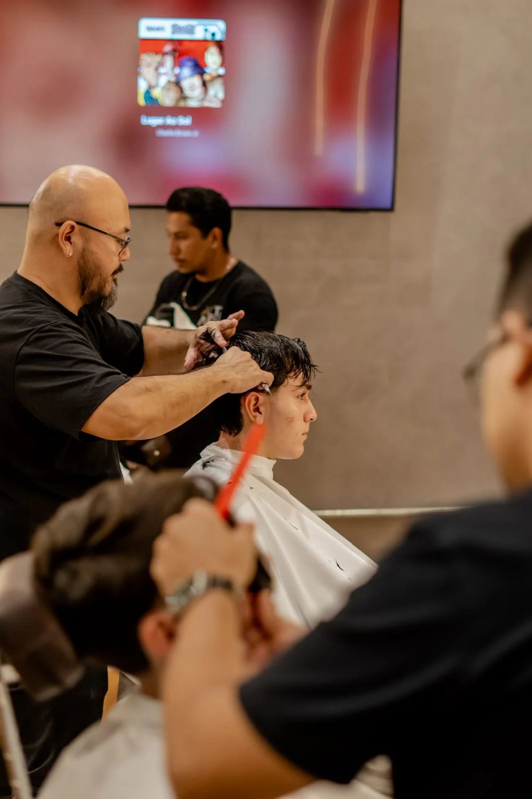 Atendimento na barbearia, com televisão ao fundo