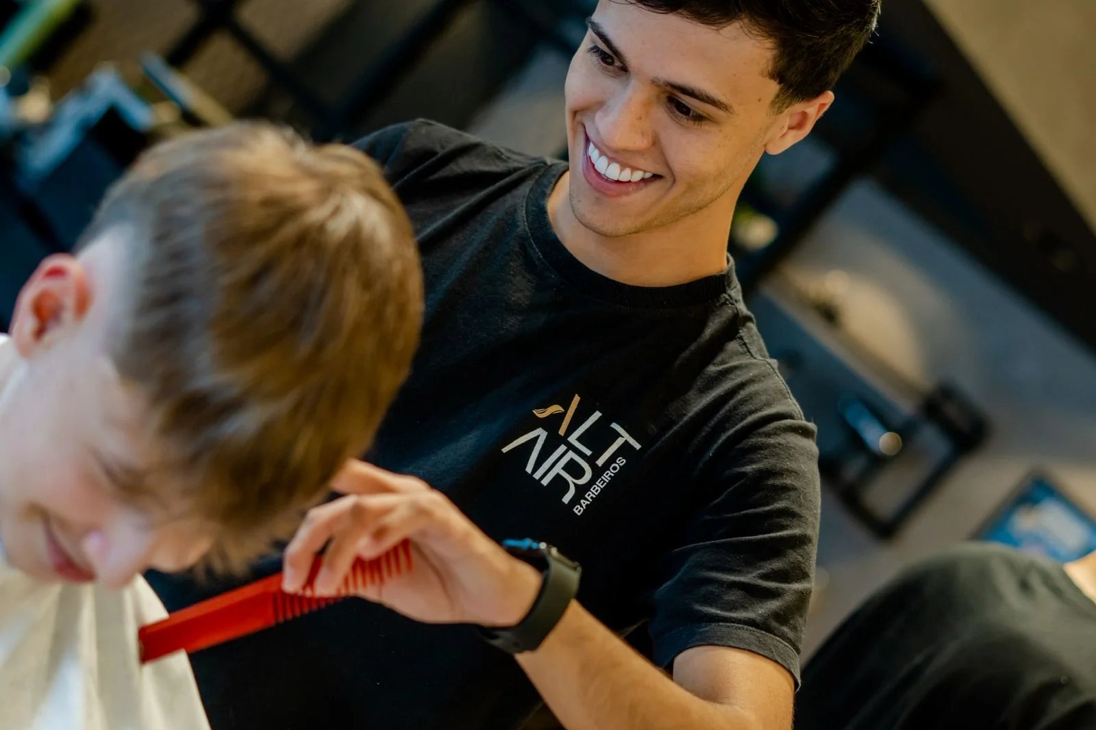 Barbeiro sorrindo enquanto corta o cabelo de um cliente